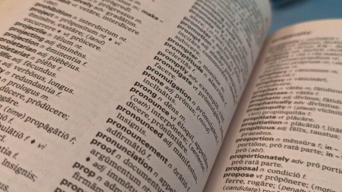 Cover image: Photo of a small Latin-English dictionary opened to the page listing words like “pronounce”, “pronunciation”, etc.