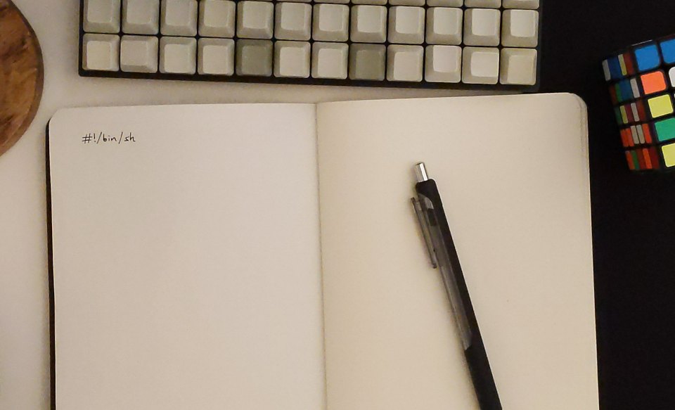 Cover image: Photo of small mechanical keyboard and notebook with
 only #!/bin/sh written in it